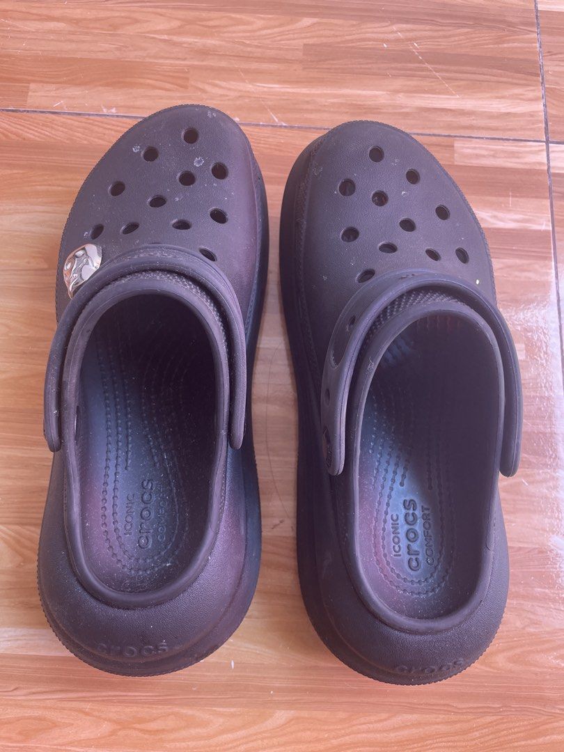 Crocs Crush Clog Black (Category: Slippers and slides) located in Cavite. Submitted by mpetalver04 (Listing ID 1469191730, Image 2). Description: - Dark brown Crocs platform clogs with chunky sole - Features iconic comfort footbed and ventilation holes - Includes heel strap with embossed logo branding - Unique silver charm attached to the side of one shoe - Condition: Shows some light scuffs and marks from normal wear.
