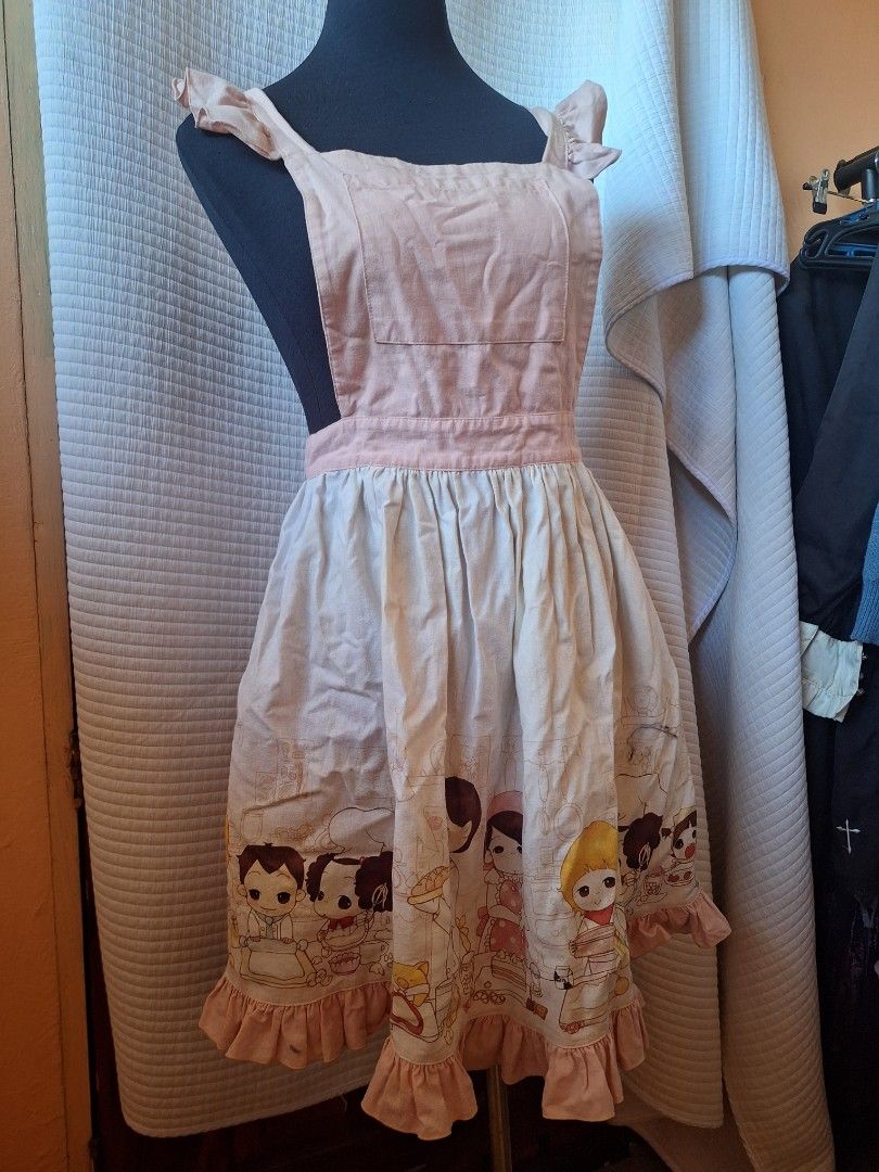 Cute Pink Apron with Anime Character Print (Category: Sleeveless) located in Balamban. Submitted by ubethan (Listing ID 1469229692, Image 2). Description: - Adorable light pink kitchen apron with anime girl print - Features a flared pleated skirt with a cute ruffled hem - Comfortable ruffled shoulder straps that cross at the back - Adjustable waist tie for a secure and flattering fit - Convenient front chest pocket for small cooking essentials - 