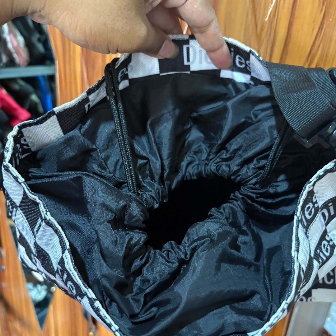 Dickies Black And White Checkered Shoulder Bag (Category: Shoulder Bags) located in Carmen. Submitted by ar_thrift00 (Listing ID 1469195980, Image 2). Description: - Brand: Dickies - Design: Black and white checker pattern with eye-catching red and yellow front logo - Details: Small logo tag near the bottom edge - Strap: Adjustable black strap with durable clips - Interior: Black lining with a secure drawstring top closure - Use: Great everyday b