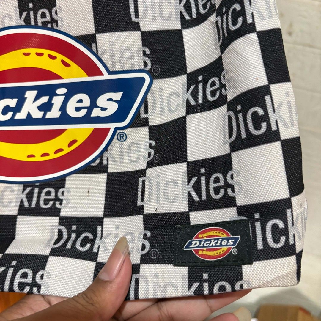 Dickies Black And White Checkered Shoulder Bag (Category: Shoulder Bags) located in Carmen. Submitted by ar_thrift00 (Listing ID 1469195980, Image 3). Description: - Brand: Dickies - Design: Black and white checker pattern with eye-catching red and yellow front logo - Details: Small logo tag near the bottom edge - Strap: Adjustable black strap with durable clips - Interior: Black lining with a secure drawstring top closure - Use: Great everyday b