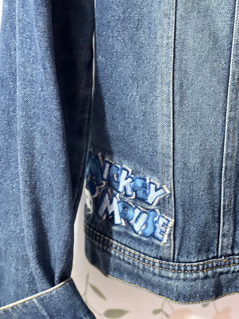 Disney Collection Denim Jacket Mickey Mouse Size S (Category: Coats, Jackets and Outerwear) located in Pasig City. Submitted by morilove (Listing ID 1469187876, Image 2). Description: - Authentic Disney Collection denim jacket in a classic blue wash - Detailed Mickey and Pluto embroidery on the back yoke - Mickey Mouse lettering embroidery near the front hem - Button-up front with custom Mickey icon embossed hardware - Functional chest flap pocke