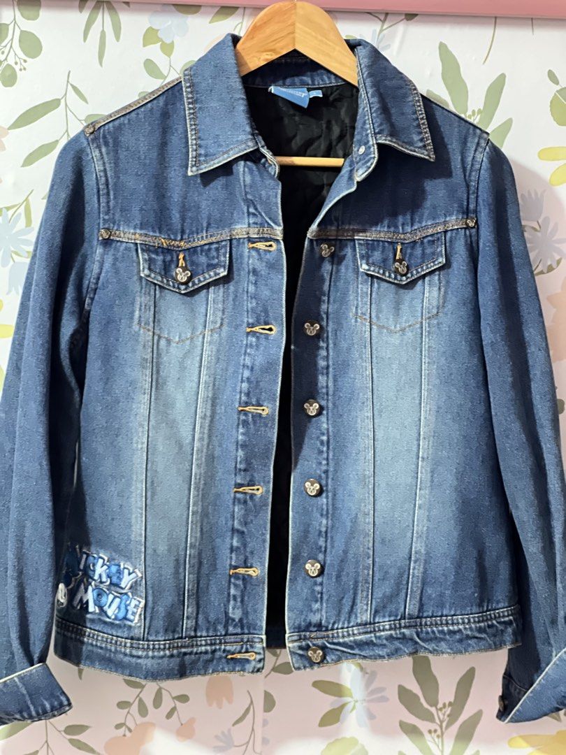 Disney Collection Denim Jacket Mickey Mouse Size S (Category: Coats, Jackets and Outerwear) located in Pasig City. Submitted by morilove (Listing ID 1469187876, Image 1). Description: - Authentic Disney Collection denim jacket in a classic blue wash - Detailed Mickey and Pluto embroidery on the back yoke - Mickey Mouse lettering embroidery near the front hem - Button-up front with custom Mickey icon embossed hardware - Functional chest flap pocke