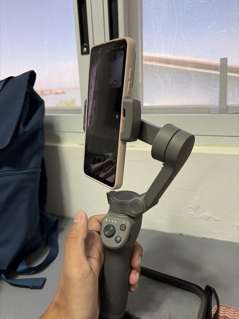 DJI Osmo Mobile Gimbal with Carrying Case (Category: Gimbals & Stabilizers ) located in Bulacan. Submitted by aaron.ascv (Listing ID 1469176024, Image 3). Description: - Model: DJI Osmo Mobile smartphone stabilizer - Color: Stylish gray with textured grip handle - Condition: 100% working, powers on fine with fully functioning LED indicators - Portability: Folds down compactly, comes with original zip carrying case - Versatility: Fits standard sma