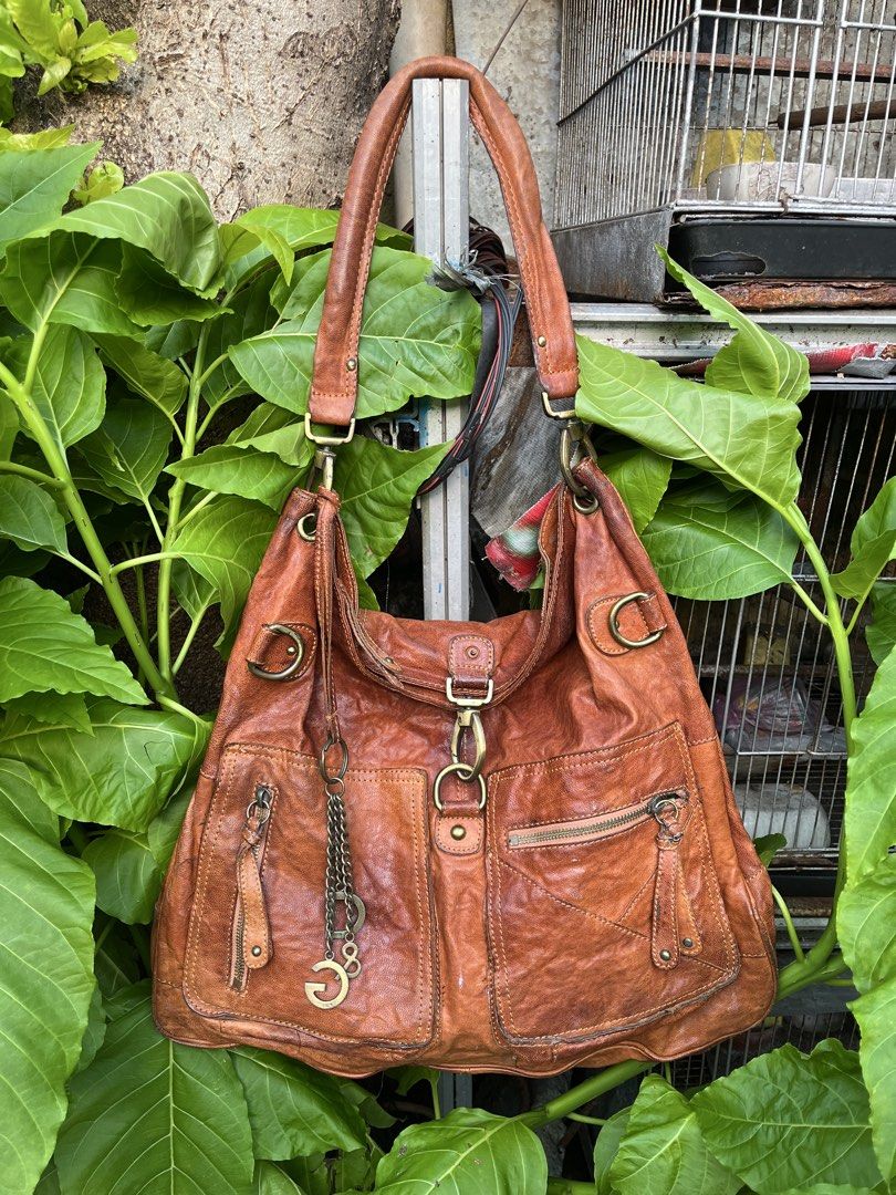 Dolce & Gabbana Brown Leather Shoulder Bag (Category: Luxury Bags & Wallets) located in Manila. Submitted by bags_2.riches (Listing ID 1469349816, Image 2). Description: - Authentic Dolce & Gabbana brown leather shoulder bag - Slouchy hobo silhouette with a rich aged leather texture - Multiple exterior pockets with secure zipper closures - Distinctive D&G metal charm hanging from the front strap - Spacious dark brown fabric-lined interior with a 