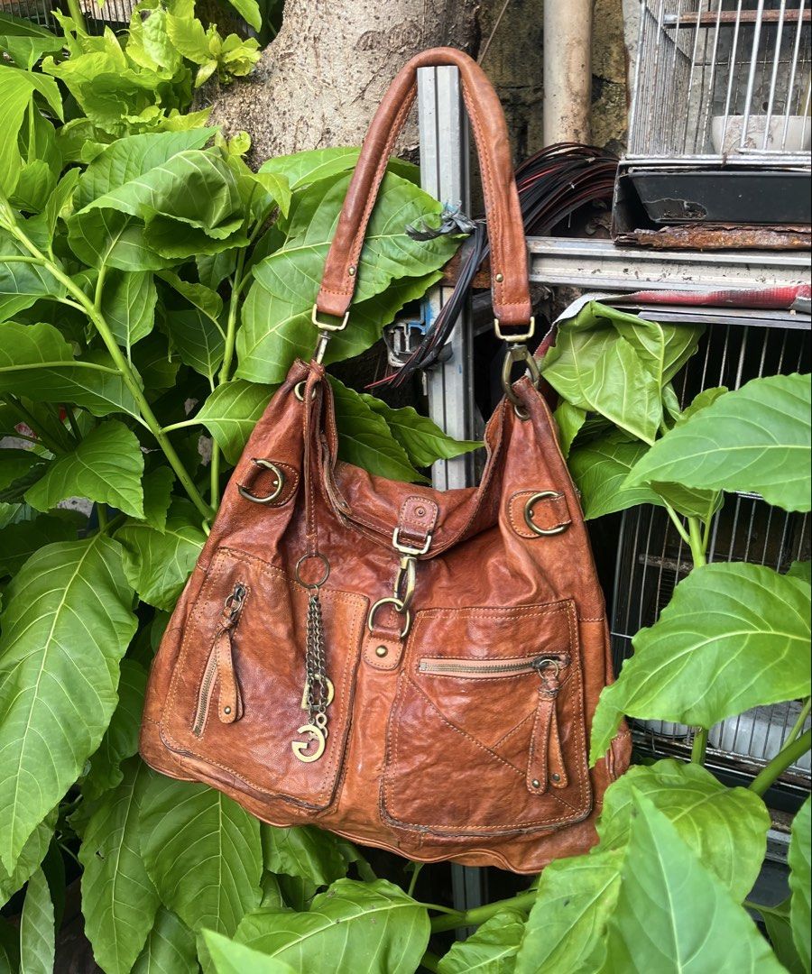 Dolce & Gabbana Brown Leather Shoulder Bag (Category: Luxury Bags & Wallets) located in Manila. Submitted by bags_2.riches (Listing ID 1469349816, Image 1). Description: - Authentic Dolce & Gabbana brown leather shoulder bag - Slouchy hobo silhouette with a rich aged leather texture - Multiple exterior pockets with secure zipper closures - Distinctive D&G metal charm hanging from the front strap - Spacious dark brown fabric-lined interior with a 