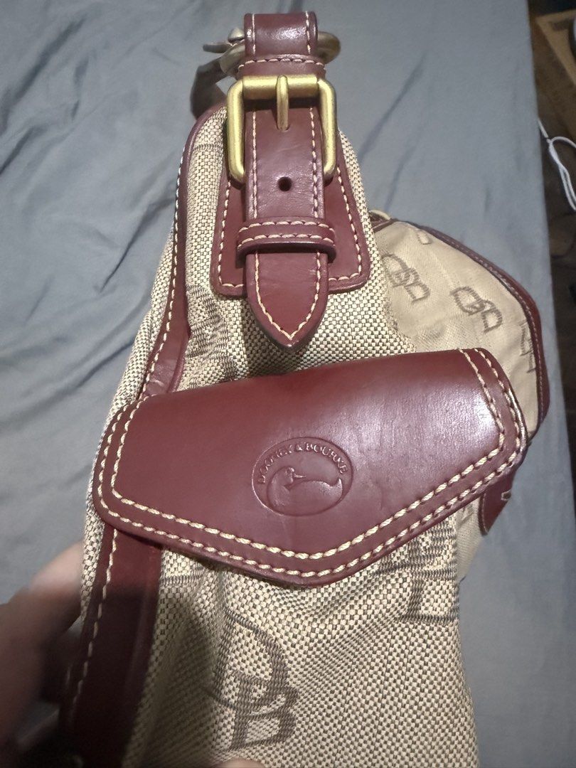 Dooney & Bourke Monogram Shoulder Bag Brown (Category: Luxury Bags & Wallets) located in Cainta. Submitted by mykee1 (Listing ID 1469228335, Image 3). Description: - Authentic Dooney & Bourke shoulder bag - Tan fabric body with iconic allover DB monogram print - Dark brown leather trim and single adjustable strap - Secure zip top closure with brass-tone hardware - Structured curved base with reinforced leather bottom corners - Classic Y2K early 2