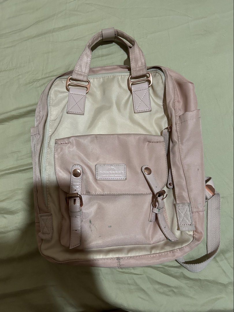 Doughnut Macaroon Backpack Pastel Pink Cream (Category: Backpacks) located in Quezon City. Submitted by temssoleil (Listing ID 1469315344, Image 2). Description: - Brand: Doughnut Macaroon - Used thrice only, there's a little scratch of pen but it can be erased - Colorway: Pastel pink and cream with rose gold hardware - Features: Front pouch pocket with buckle closures, brand patch, adjustable shoulder straps, and top grab handles with snap butto