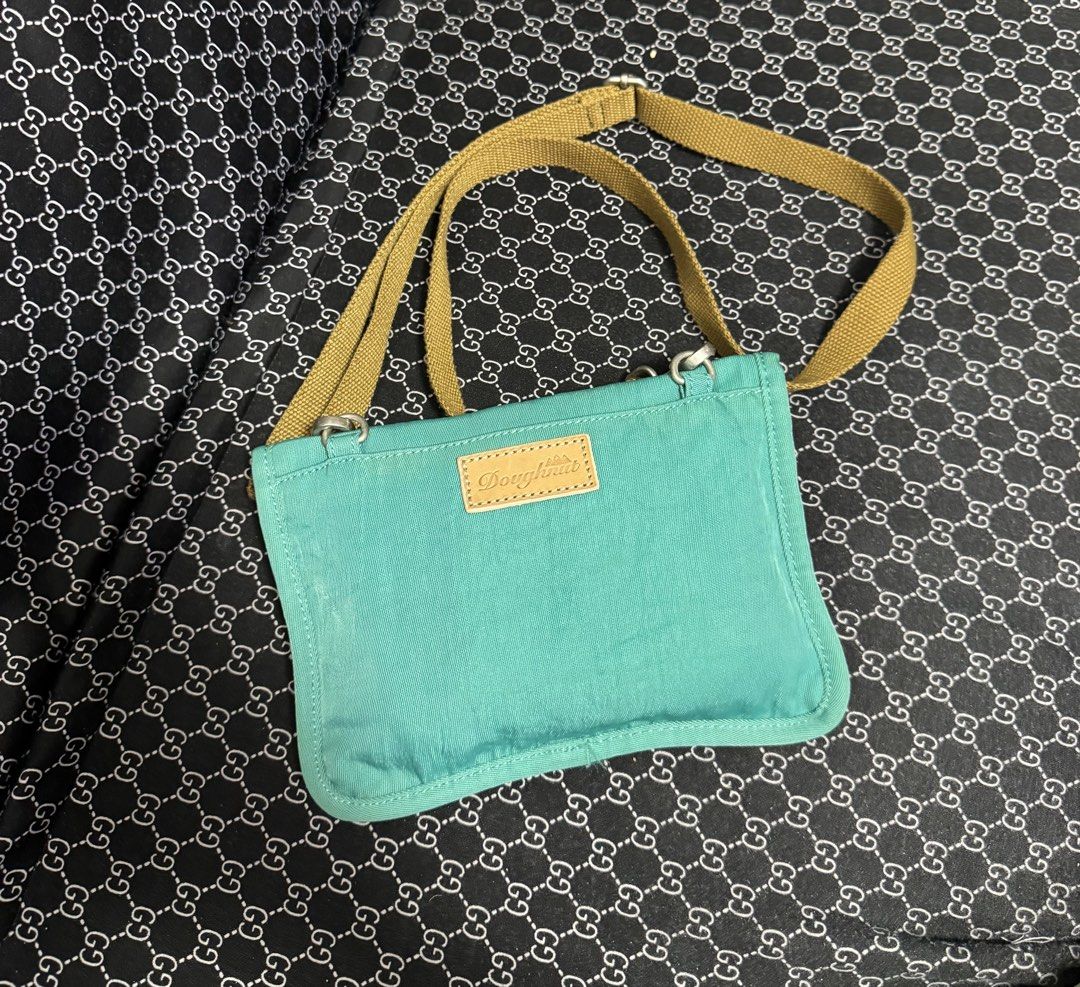 Doughnut Small Teal Adjustable Crossbody Belt Bag (Category: Cross-body Bags) located in Manila. Submitted by esparciake75752 (Listing ID 1469199061, Image 2). Description: - Brand: Doughnut - Color: Teal and yellow with a tan strap - Features: Leather brand patch, snap buttons on back flap, and adjustable strap - Size: Compact, ideal for daily essentials and hands-free convenience - Condition: Clean fabric inside and out, ready for use.