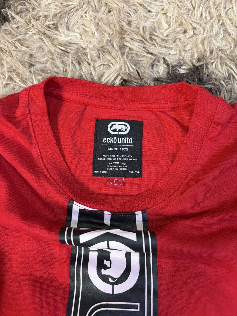 Ecko Unltd. Red T-Shirt Size L (Category: Tshirts & Polo Shirts ) located in Manila. Submitted by _valuevault777 (Listing ID 1469179416, Image 3). Description: - Brand: Ecko Unltd. - Color: Bright red with black and white vertical graphic stripe - Size: L (Large) - Material: 100% cotton, made in China - Details: Features matching branded patches on the left sleeve and bottom hem - Condition: Excellent / Ready to wear.