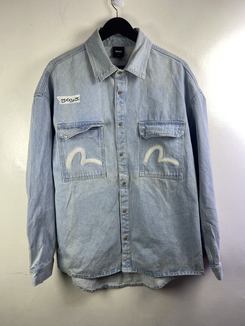 Evisu Light Blue Denim Shirt Size XL (Category: Tshirts & Polo Shirts ) located in Manila. Submitted by declutterpromax (Listing ID 1469289928, Image 1). Description: - Brand: Evisu - Color: Light wash blue - Size: XL - Details: Button-down front with metal snap buttons - Pockets: Dual front chest pockets with iconic embroidered white seagull branding - Hem: Curved hemline design - Authenticity: Crafted with pride tag on the inner collar - Condit