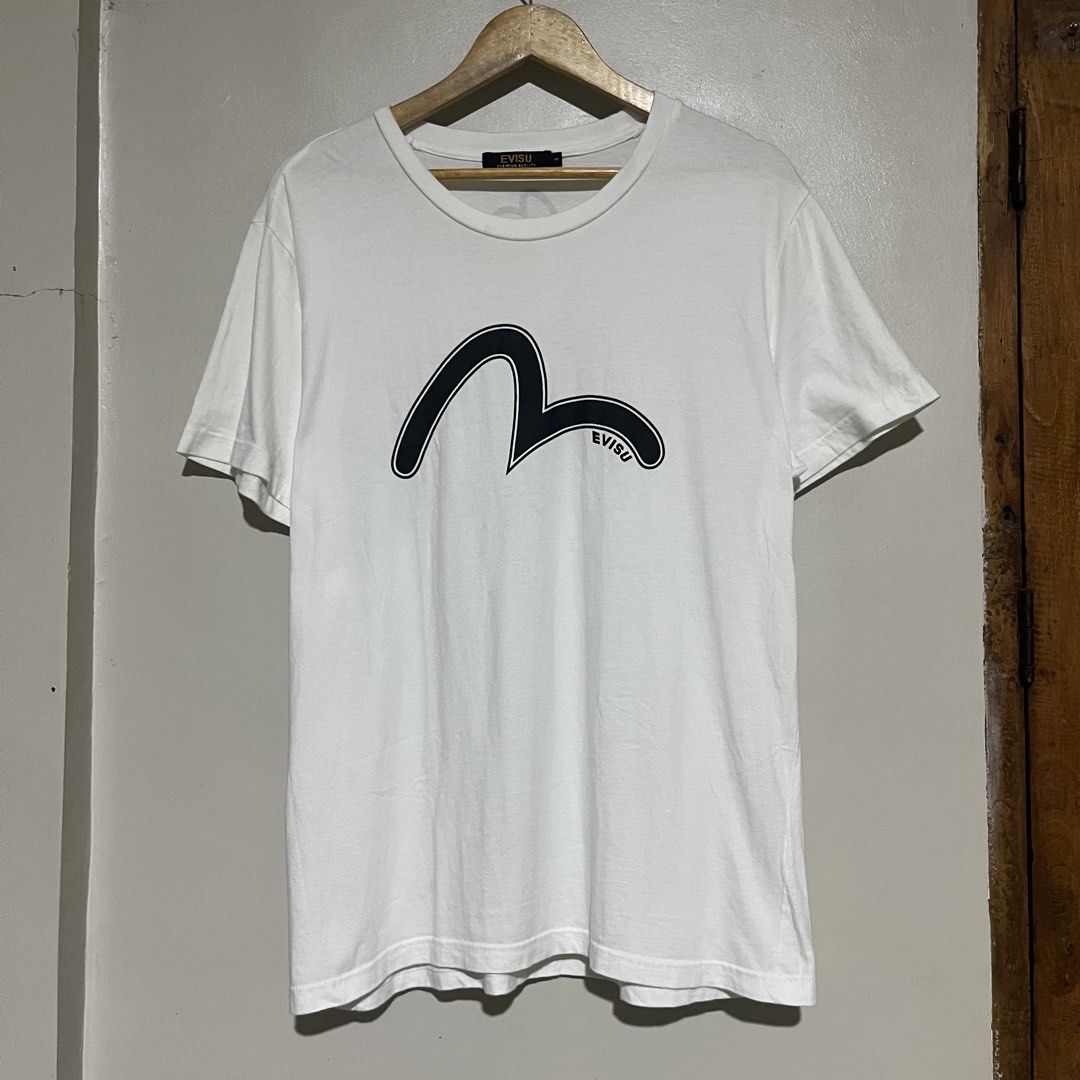 Evisu White Graphic T-Shirt (Category: Tshirts & Polo Shirts ) located in Argao. Submitted by secondcyclecollection (Listing ID 1469294048, Image 1). Description: - Brand: Evisu - Color: White with black logo graphic on front - Details: Small logo on back neck, black and gold collar label, authenticity QR code tag on inner seam - Fit: Regular fit, classic crew neck, short sleeves - Material: Clean, comfortable cotton - Condition: Brand new / Exce