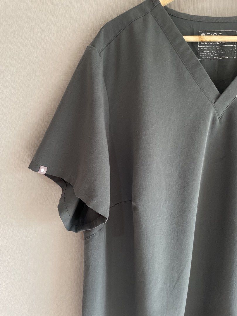 FIGS Catarina Scrub Top Dark Grey (Category: Activewear) located in Mataasnakahoy. Submitted by zero4thrift (Listing ID 1469217054, Image 3). Description: - Brand: FIGS - Style: Catarina (V-neck, short sleeves) - Color: Dark Grey - Details: Single chest pocket with FIGS logo label - Material: 72% polyester, 21% rayon, 7% spandex - Care: Machine washable - Condition: Excellent pre-loved / Like new - Perfect for healthcare professionals looking for