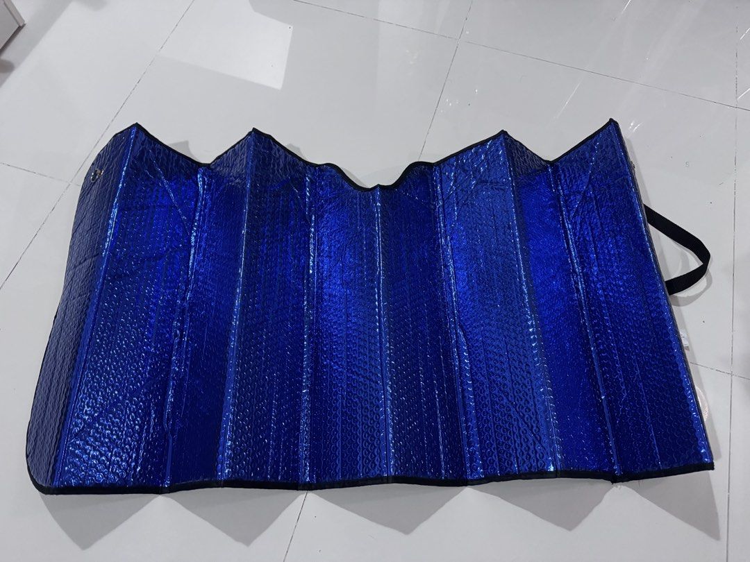Foldable Windshield Sun Shade (Category: Other Automotive Parts and Accessories) located in Taguig. Submitted by xervin (Listing ID 1469268464, Image 3). Description: - Item: Foldable Windshield Sun Shade - Color: Blue exterior with reflective silver interior - Material: Bubble foil insulation for maximum heat protection - Design: Foldable accordion style with securing strap for easy storage - Condition: Good as new, clean and ready to use - Func