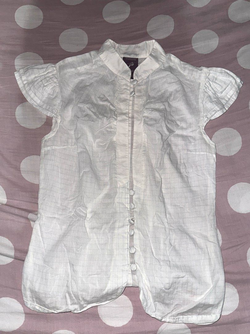 Folded & Hung White Plaid Button-Down Blouse 🤍 (Category: Blouses) located in Valenzuela. Submitted by prelovedbykkaisha (Listing ID 1469226262, Image 2). Description: Size: Small Color: White with subtle plaid stripes Design: Ruffled short sleeves, collar, and front buttons Condition: Like new Perfect for a cute, clean-girl, or coquette-inspired outfit! Can be paired with jeans, skirts, or trousers. 💌.