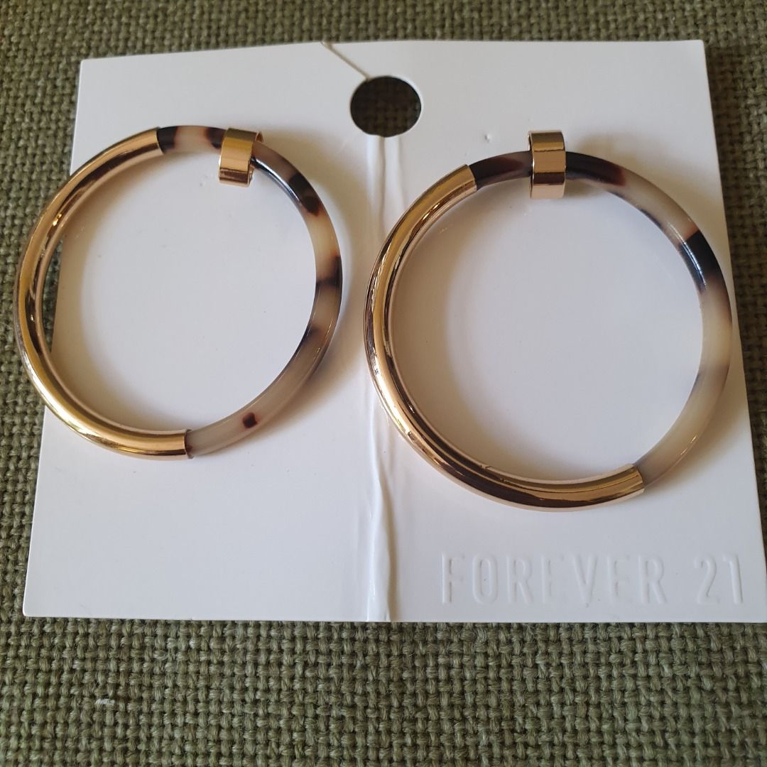 Forever 21 Gold and Brown Tortoise Shell Like Earrings (Category: Earrings) located in Caloocan City. Submitted by mma_222 (Listing ID 1469190268, Image 2). Description: - Brand: Forever 21 - Design: Large circular hoops with gold-tone hardware and brown tortoise shell pattern - Size: Approximately 2 inches across - Condition: Brand new, never worn, on original cardboard store backing.