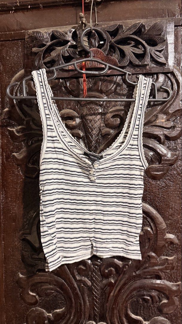 Forever 21 Striped Ribbed Tank Top Size S (Category: Sleeveless) located in Las Pinas. Submitted by aliah2703 (Listing ID 1469173563, Image 1). Description: - Brand: Forever 21 - Size: S - Color: White with dark blue stripes - Details: Scoop neckline, button-up front placket, lettuce trim on straps and collar - Material: Lightweight and comfortable - Style: Versatile basic piece, perfect to match with high-waisted denim or skirts for everyday wea