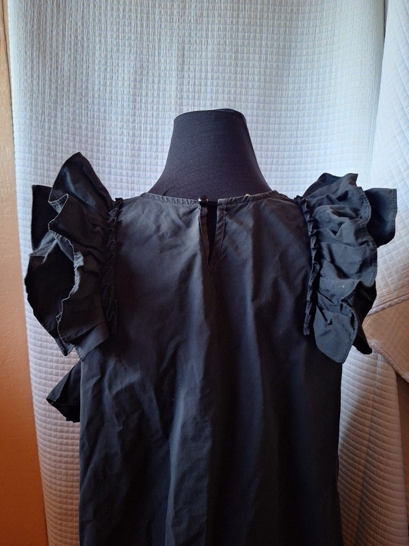 Frill Cute Black ruffled sleeveless top with back keyhole button (Category: Sleeveless) located in Balamban. Submitted by ubethan (Listing ID 1469232698, Image 2). Description: - Color: Black - Style: Sleeveless top with dramatic ruffled shoulders and asymmetric hem - Neckline: Scoop neck with back keyhole and button closure - Fabric: Lightweight with great movement - Versatility: Perfect for both casual daytime looks and dressed-up evening outfi