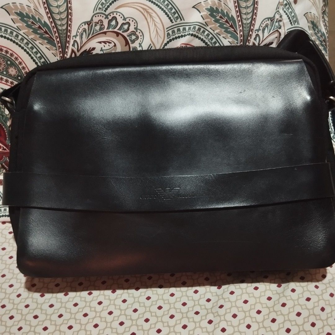 Giorgio Armani Black Leather Messenger Bag (Category: Sling Bags) located in Manila. Submitted by lene48 (Listing ID 1469238908, Image 1). Description: Black messenger bag by Giorgio Armani. Leather flap front with embossed logo band across the middle. Adjustable shoulder strap with metal hardware. Inside has branded fabric lining, zip pocket, and slip compartments. Clean interior, sturdy build, great everyday carryall..