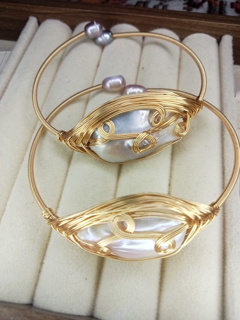 Gold wire wrapped baroque pearl open bangles (Category: Bracelets) located in Davao. Submitted by kimpoycaye62726 (Listing ID 1469328495, Image 1). Description: - Set of 2 gold tone wire-wrapped bangles ₱500 each - Large baroque pearl centerpieces with beautifully irregular shapes - Extra small pearls detailing the ends of the bands - Flexible open cuff design for easy slip-on wear - Eye-catching statement jewelry that sparkles in the light.