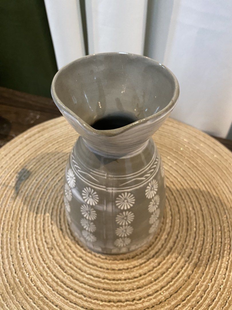 Gray ceramic vase with white floral pattern and spout (Category: Vases & Decorative Bowls) located in San Pedro. Submitted by jingay81 (Listing ID 1469372082, Image 3). Description: - Material: Sturdy gray ceramic - Design: Vertical white floral pattern with a flared top rim and pouring spout - Dimensions: Approximately 17 cm tall - Use: Perfect as a tabletop decor piece or a small accent vase - Condition: Excellent, ready for display.