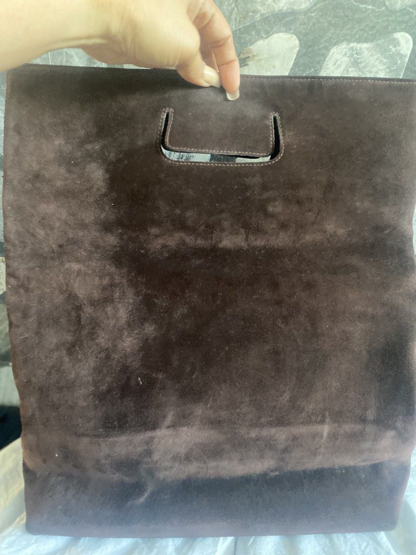Gucci Brown Suede Tote Handbag (Category: Luxury Bags & Wallets) located in Bacolod City. Submitted by chuchaystuffs (Listing ID 1469165429, Image 2). Description: - Brand: Gucci - Material: Brown suede with dark fabric lining - Design: Structured cut-out handle - Pockets: Exterior back zip pocket and interior zip pocket - Details: Embossed Gucci leather tag inside - Condition: Light wear and scuffing from regular handling.