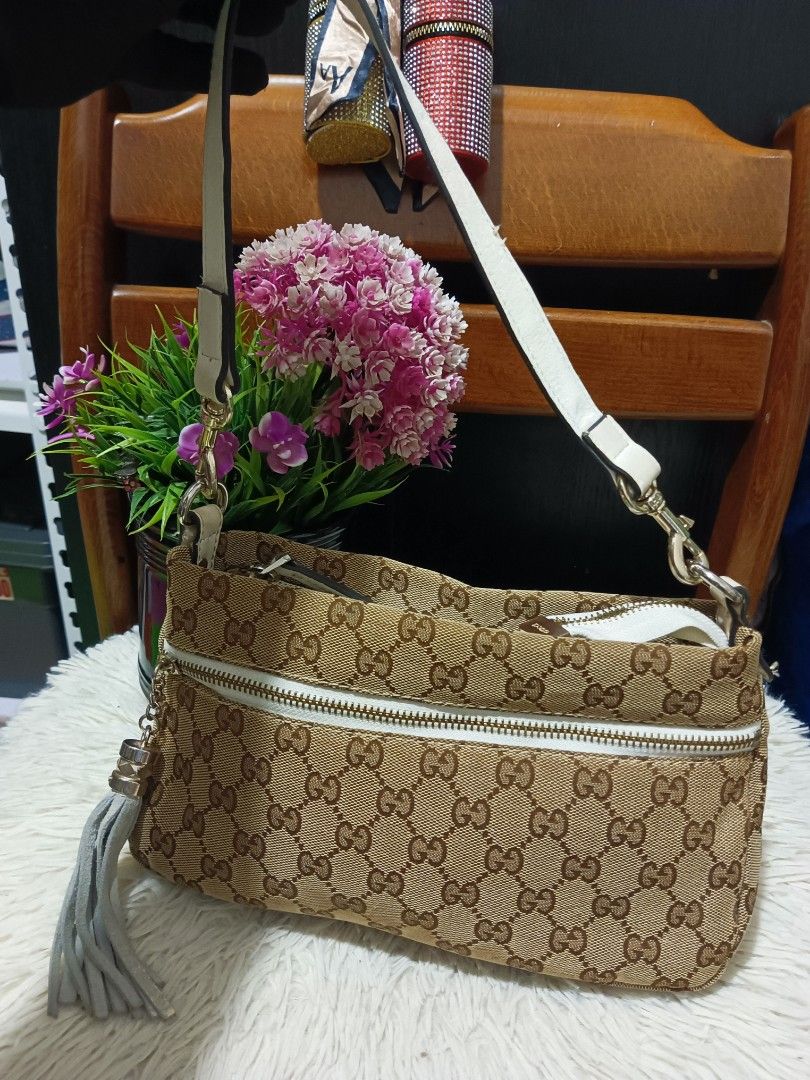 Gucci GG Canvas Shoulder Bag (Category: Luxury Bags & Wallets) located in Digos. Submitted by chihanu (Listing ID 1469194577, Image 1). Description: - Gucci shoulder bag in classic beige and brown monogram canvas - Stylish white leather trim and matching strap with gold-tone hardware - Playful grey tassel charm on the front zip pocket - Clean interior with a well-structured shape - Great everyday size to fit all your daily essentials.