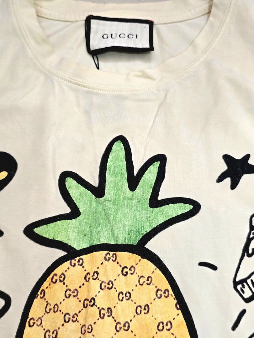GUCCI "Pineapple & Pair 'N' Dice" Doodle Graphic Tee (Category: Luxury Apparel) located in Pasay City. Submitted by seventhrift.26 (Listing ID 1469280086, Image 2). Description: ​Size: Medium (M) ​Color: Off-White / Light Cream ​Condition: Pre-loved / Good Condition (Please refer to detailed photos for exact condition) ​✨ Features the iconic pineapple GG monogram print with doodle graphics on front and sleeve. Original tags attached. Clean and we