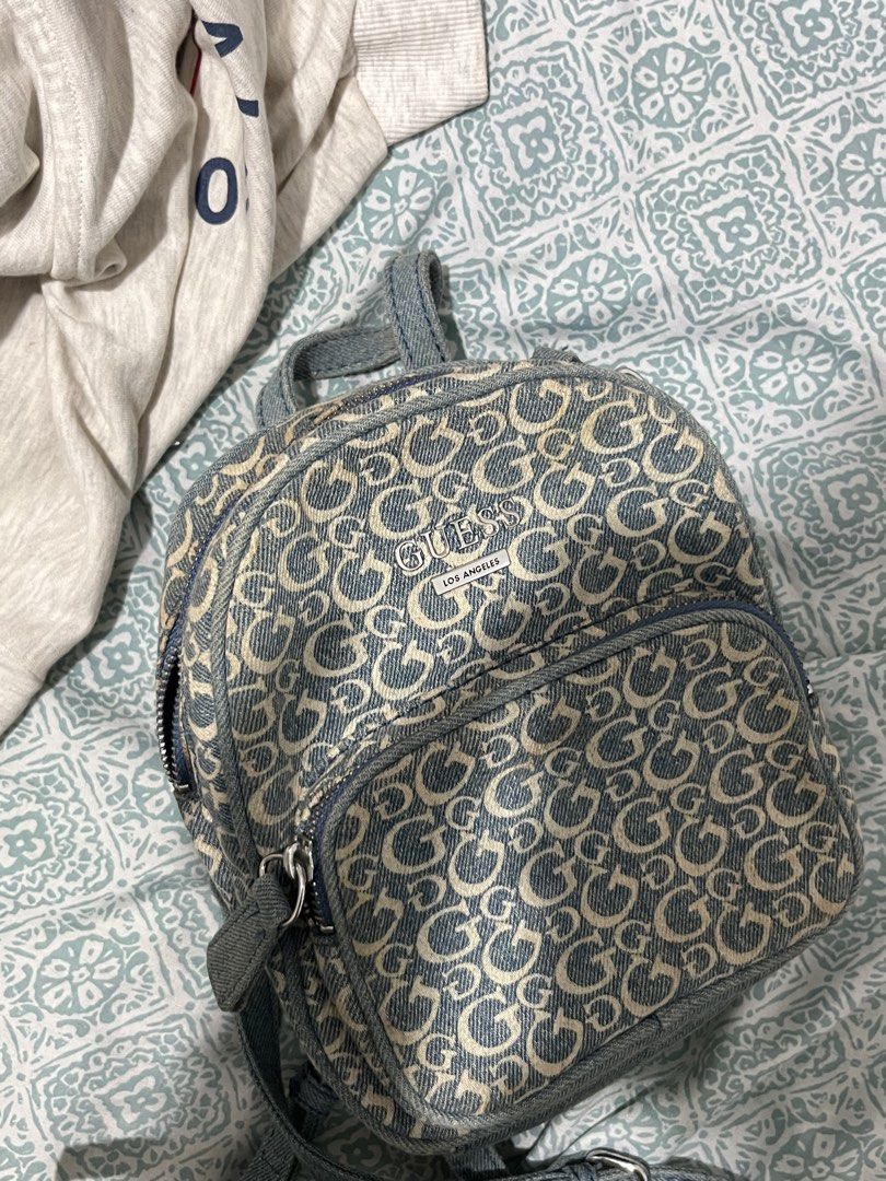 Guess Los Angeles Denim Monogram Mini Backpack (Category: Backpacks) located in Rizal. Submitted by cwassnut (Listing ID 1469217017, Image 1). Description: - Brand: Guess Los Angeles - Material: Blue denim with all-over monogram 'G' pattern - Hardware: Silver-tone with front metal logo plaque - Compartments: Main compartment with internal zip pocket plus front zipped pocket - Straps: Adjustable denim shoulder straps and top grab handle - lightly 
