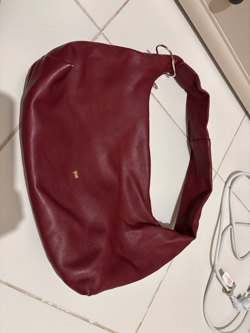 GVN Maroon Red Leather Shoulder Bag (Category: Shoulder Bags) located in Pasay City. Submitted by _mcrnj (Listing ID 1469336432, Image 1). Description: - Color & Material: Deep maroon red in textured faux leather - Design: Soft, slouchy shape with a wide strap and chic gold hardware ring detail - Interior: Clean white canvas lining - Closure: Secure top zip closure - Condition: Good pre-loved condition with a small scuff mark on one bottom corner