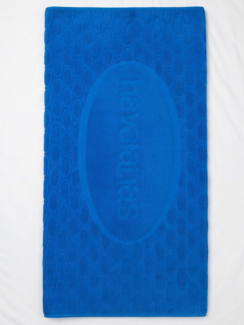 Havaianas Blue Beach Towel (Category: Bedding & Towels) located in Quezon City. Submitted by aussomefinds (Listing ID 1465852053, Image 1). Description: - Authentic Havaianas beach towel in a vibrant bright blue shade - Features iconic embossed branding inside a large oval with a textured pebble pattern - Crafted from soft, absorbent terry cloth fabric - Generous size: approximately 39 x 57 inches - Versatile use: ideal for the beach, pool, or gy