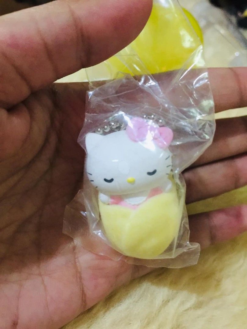 Hello Kitty Egg Sleeping Keychain Bag Charm (Category: Character Goods) located in Baguio. Submitted by izza_thrifty (Listing ID 1469167738, Image 2). Description: - Authentic Sanrio Kitty keychain figure - Adorable design: Kitty sleeping inside a fuzzy yellow egg shell with a pink bow - Soft texture exterior on the egg - Includes a small metal ball chain for easy attachment to bags, keys, or lanyards - Brand new, sealed in original clear plastic