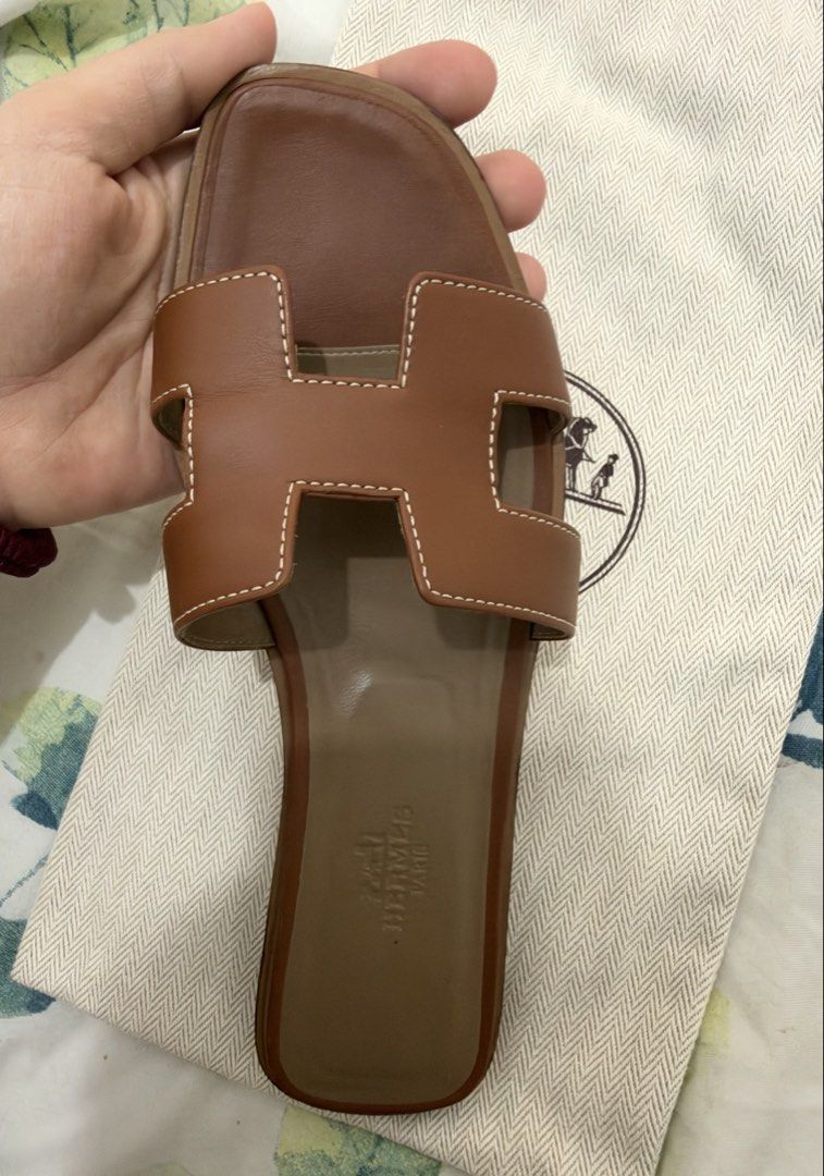 Hermes Oran Sandal gold (Category: Sneakers & Footwear) located in Manila. Submitted by mariasells05 (Listing ID 1469176025, Image 1). Description: - Authentic Hermès Oran sandals in classic brown leather - Features the iconic cutout H strap design - Comfortable flat sole with stamped logo on the footbed - Serial number stamped securely under the strap - Comes with original branded dust bag.