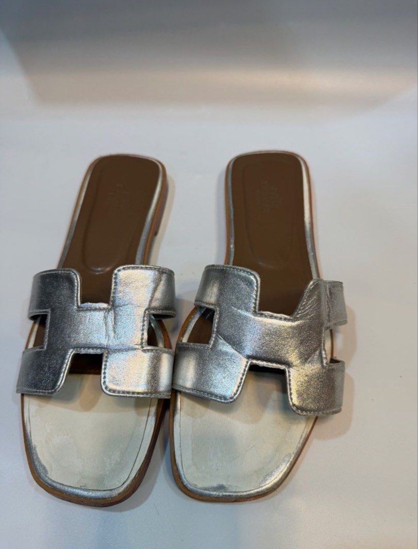 Hermes Silver Leather Sandals Size 37 (Category: Flats & Sandals) located in Cebu City. Submitted by raiiilau (Listing ID 1469338941, Image 1). Description: - Brand: Hermès - Style: Iconic H strap slip-on sandals - Color: Metallic Silver - Size: 37 (Made in Italy) - Material: Premium leather upper and sole - Condition: Flat leather soles with minor wear from previous use - Perfect luxury staple for the summer season.