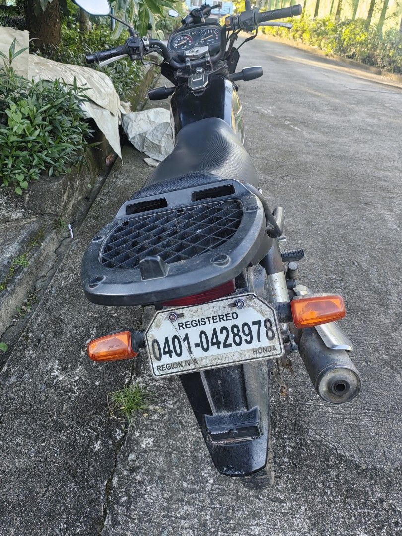 Honda TMX motorcycle (Category: Motorbikes for Sale) located in Silang. Submitted by jamessseller (Listing ID 1469247546, Image 2). Description: Black Honda TMX motorcycle. Manual transmission with standard handlebars and round headlight. Rear cargo rack included, plus registered license plate mounted at the back. Spoke wheels on both front and rear. Frame and exhaust show some rust spots from use. Engine block intact with kick starter..
