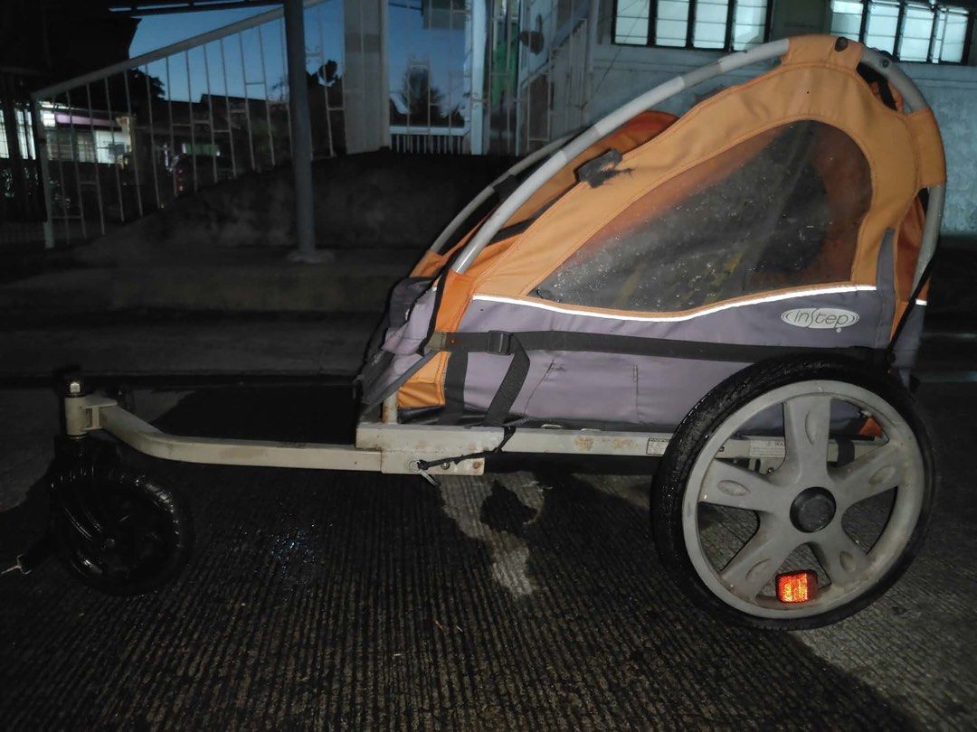 Instep Orange and Grey Bicycle Trailer (Category: Bicycles) located in Binan City. Submitted by maggierabi01434 (Listing ID 1469268273, Image 2). Description: - Brand: Instep - Color: Orange and grey - Capacity: Double seating with safety harnesses - Wheels: Large rear wheels + front swivel wheel attachment - Protection: Clear plastic window canopy against wind and rain - Storage: Rear cargo storage area with safety reflectors - Storage/Portabili