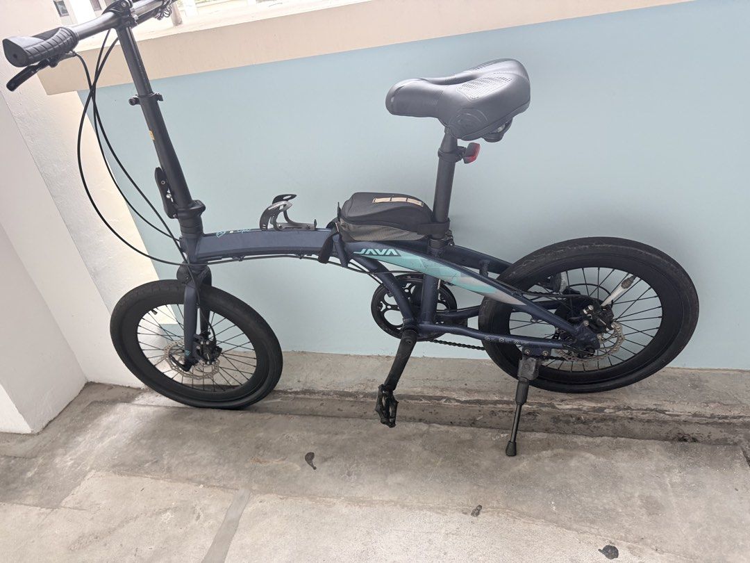 JAVA Folding Bicycle Blue (Category: Bicycles) located in Singapore. Submitted by jayankaji (Listing ID 1469187243, Image 1). Description: - Brand/Model: JAVA folding bicycle - Color: Dark blue with teal accents - Condition: Tyres and frame in tidy shape - Brakes: Front and back disc brakes - Accessories included: Small top tube frame bag, handlebar stem bottle cage, kickstand, and flat pedals - Portability: Compact design that folds easily for s