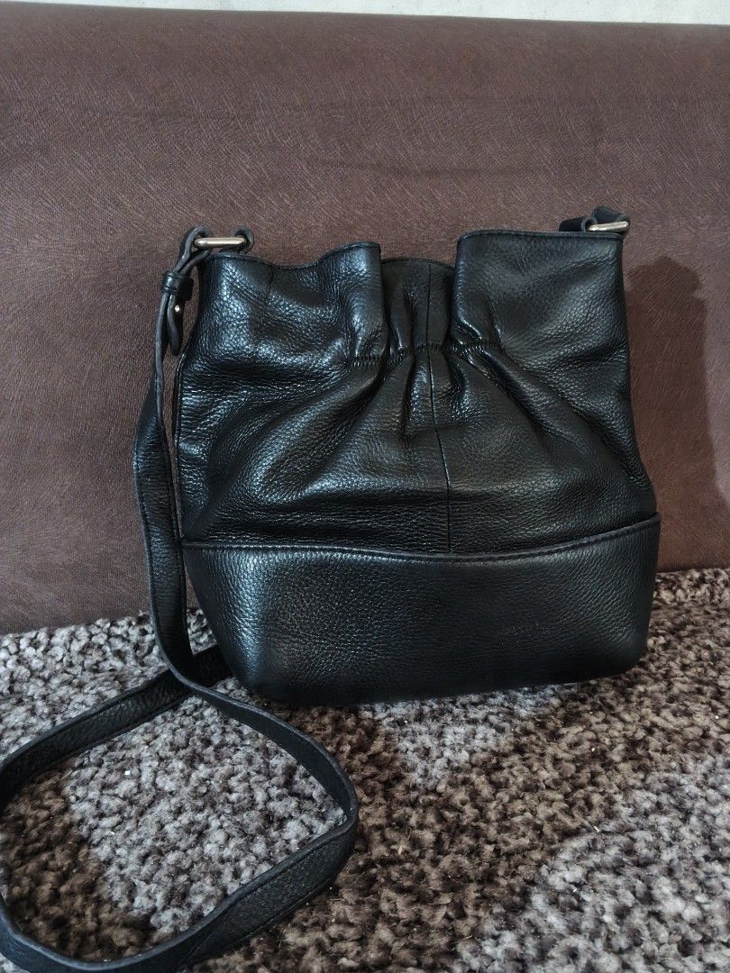 Kate Spade Black Leather Bucket Bag (Category: Luxury Bags & Wallets) located in Bulacan. Submitted by shayneerri02343 (Listing ID 1469173981, Image 2). Description: - Brand: Kate Spade New York - Material: Genuine black pebbled leather with gold-tone hardware - Closure: Drawstring with a stylish front bow detail - Strap: Long, adjustable crossbody strap - Design: Structured base with metallic logo lettering and a clean interior lining - Capacity