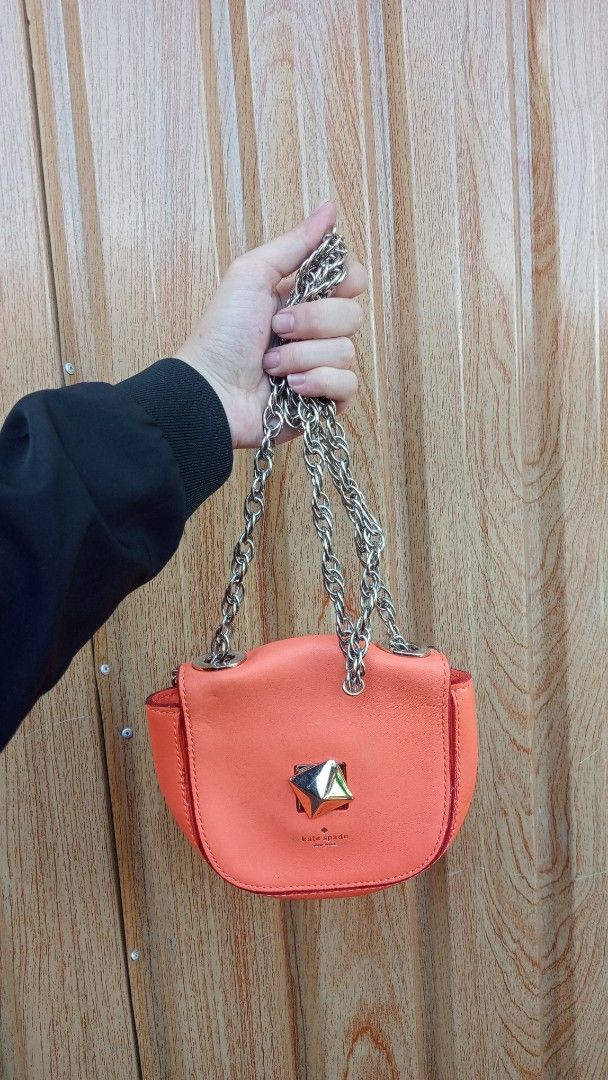 Kate Spade Orange Leather Shoulder Bag with Chain Strap (Category: Luxury Bags & Wallets) located in Cagayan de Oro. Submitted by zoe-ini (Listing ID 1469208274, Image 1). Description: - Brand: Kate Spade - Material: Premium Leather - Color: Bright Orange - Design: Rounded shape with a bold front pyramid stud accent and clean stitching - Strap: Chunky silver chain for shoulder or arm carry - Condition: Excellent, clean and well-maintained - Style
