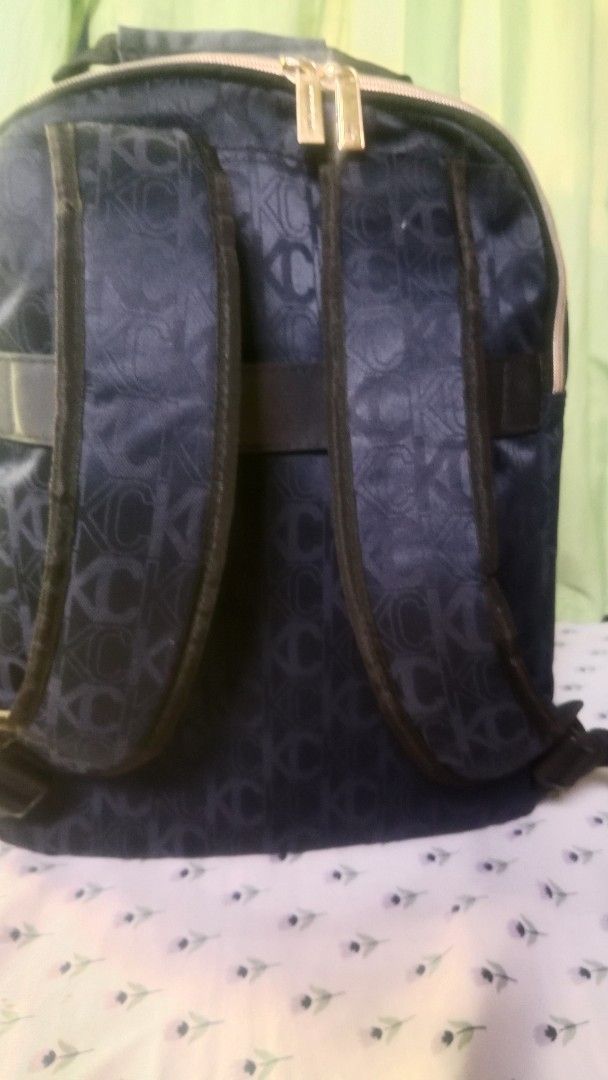 Kenneth Cole New York Monogram Print Navy Backpack (Category: Backpacks) located in San Miguel. Submitted by chriswajer65155 (Listing ID 1469233076, Image 3). Description: - Brand: Kenneth Cole New York - Color/Pattern: Dark blue with all-over monogram - Hardware: Premium gold-tone with branded metal plaque - Compartments: Multiple zip closures and a front zipped pocket - Pockets: Convenient side slip pockets - Straps: Adjustable with padded desi