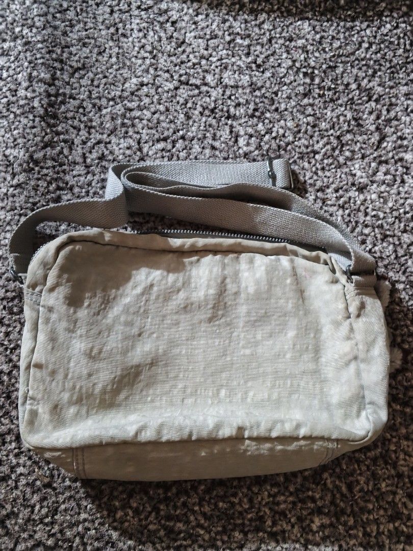 Kipling beige nylon crossbody bag with monkey keychain (Category: Cross-body Bags) located in Bulacan. Submitted by shayneerri02343 (Listing ID 1469189040, Image 3). Description: - Brand: Kipling - Material: Durable nylon - Color: Versatile beige / neutral taupe - Strap: Adjustable for comfortable wear - Exterior: Front flap pocket, zipper pocket, and circular logo patch - Interior: Secure zip closure main compartment, inner zipper pocket, and op