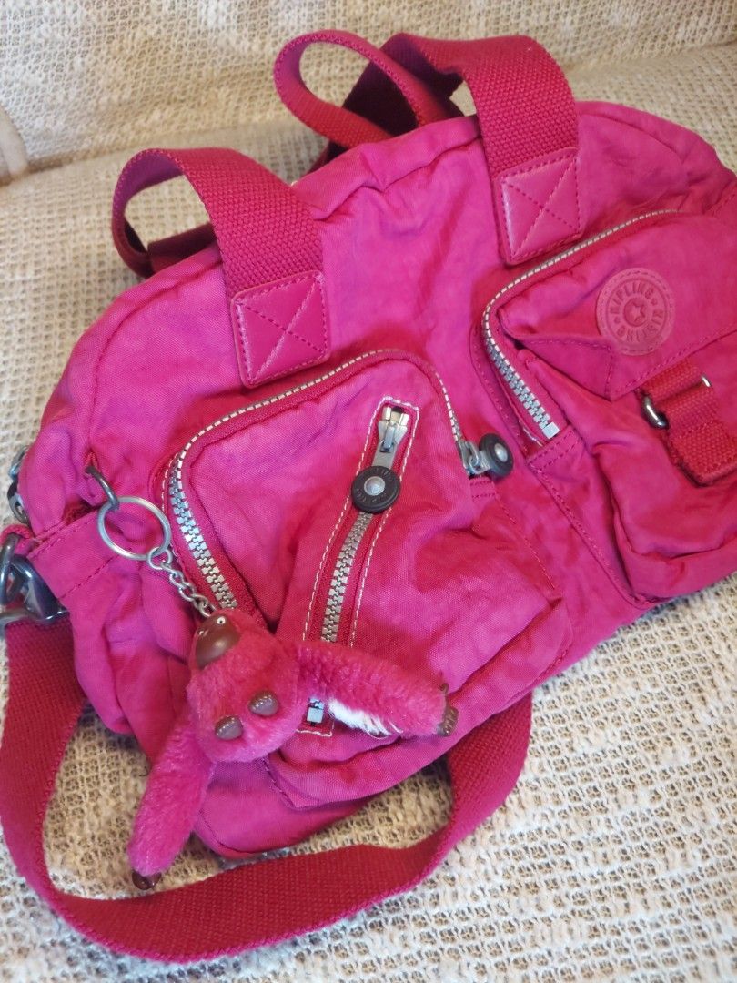 Kipling Pink Nylon Shoulder Bag Handbag (Category: Shoulder Bags) located in Quezon City. Submitted by never_a_clutter (Listing ID 1469204298, Image 2). Description: - Authentic Kipling shoulder bag in a vibrant bright pink color - Made from durable, signature crinkled nylon - Versatile carry options with dual top handles and an adjustable crossbody strap - Includes the iconic matching furry monkey keychain - Multiple exterior front zip pockets f