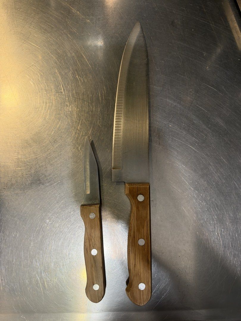 Kitchen knife set with wooden handles (Category: Knives & Chopping Boards) located in Manila. Submitted by garagesalebykoda (Listing ID 1469201175, Image 1). Description: - 2-piece kitchen knife set (1 large chef knife, 1 smaller paring knife) - Durable stainless steel blades with light cleaning marks from regular use - Sturdy wooden handles with secure riveted construction - Natural wood grain variations on each handle - Reliable and sharp every