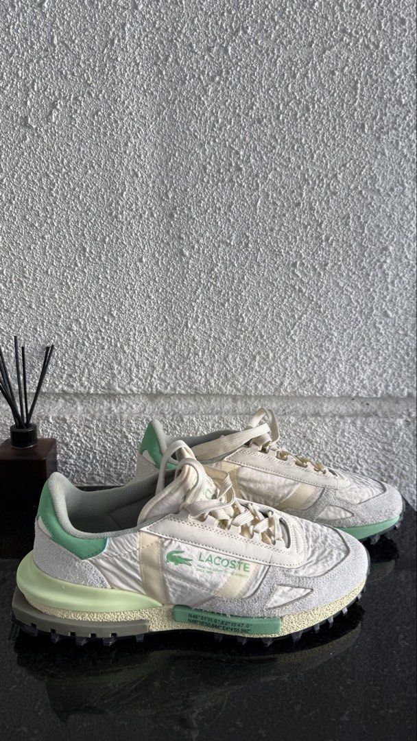 Lacoste Elite Active (Category: Sneakers) located in Pasig City. Submitted by byz94 (Listing ID 1469168314, Image 2). Description: White and green Lacoste sneakers with suede panels and chunky treaded rubber soles. Branding printed on the side panel and tongue. Coordinates text printed along the midsole and upper. Textured nylon upper material. Grippy black outsole with green and cream accents. Laced front closure with flat woven laces..
