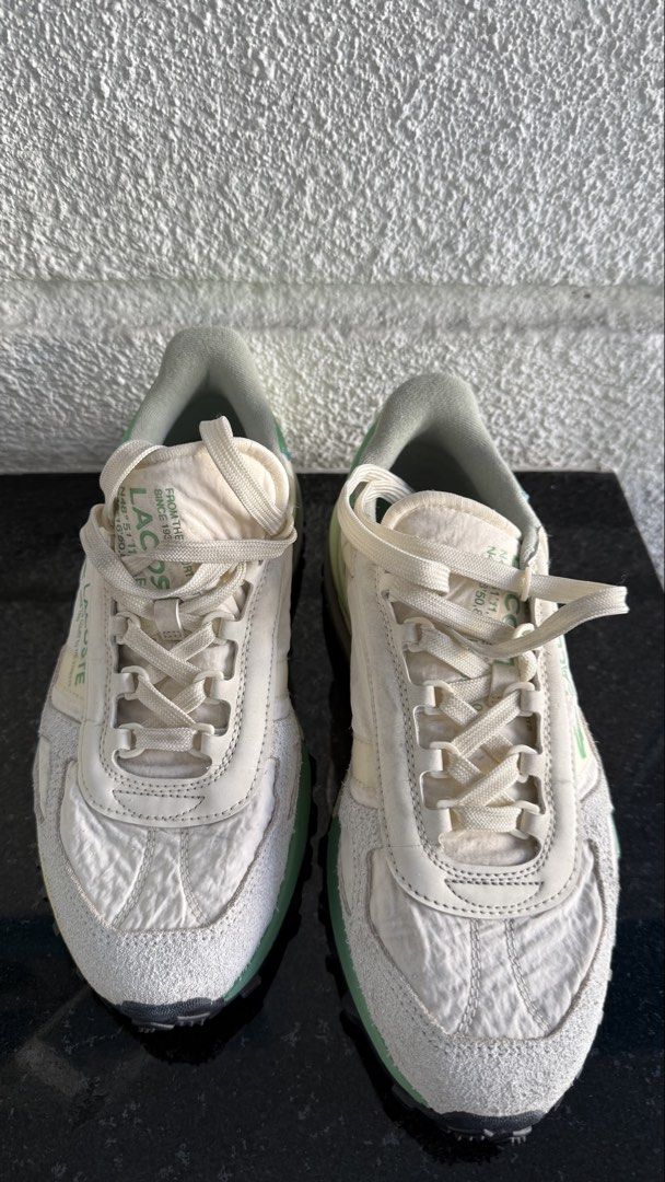 Lacoste Elite Active (Category: Sneakers) located in Pasig City. Submitted by byz94 (Listing ID 1469168314, Image 1). Description: White and green Lacoste sneakers with suede panels and chunky treaded rubber soles. Branding printed on the side panel and tongue. Coordinates text printed along the midsole and upper. Textured nylon upper material. Grippy black outsole with green and cream accents. Laced front closure with flat woven laces..