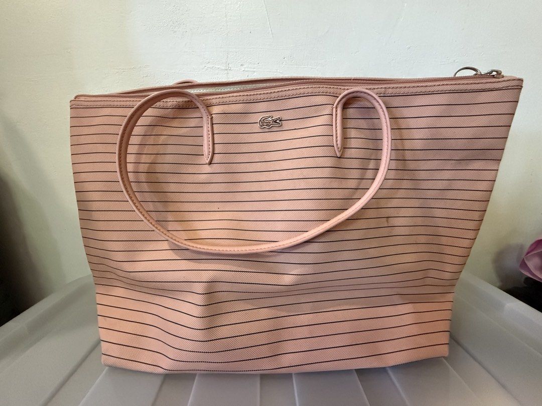 Lacoste Pink Striped Tote Bag (Category: Tote Bags) located in Manila. Submitted by soju2026 (Listing ID 1469163836, Image 1). Description: - Brand: Lacoste - Design: Pink canvas with classic horizontal black stripes - Logo: Iconic silver-tone crocodile logo near the top - Closure: Secure top zipper to keep your belongings safe - Straps: Comfortable twin shoulder straps in matching pink - Base: Clean, structured base that stands upright on its ow