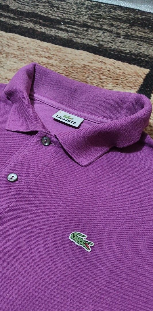 Lacoste Purple Polo Shirt (Category: Tshirts & Polo Shirts ) located in Manila. Submitted by ianmontede19006 (Listing ID 1469336313, Image 3). Description: - Brand: Lacoste (Manufactured by Devanlay) - Color: Vibrant Purple - Material: 100% classic cotton piqué - Design: Short sleeves, standard collar, two-button placket with dark buttons - Detail: Iconic green crocodile logo embroidered on the chest - Condition: Clean inside label, well-maintain