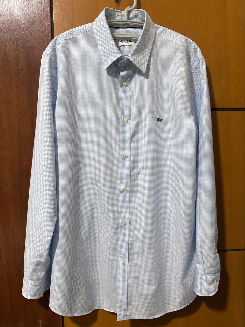Lacoste Regular Fit Gingham Long Sleeve Shirt (Category: Formal Shirts) located in Quezon City. Submitted by aussomefinds (Listing ID 1465361567, Image 1). Description: - Brand: Lacoste - Style: Long sleeve button-up shirt in light blue and white gingham check - Fit: Regular fit with a classic collar and single-button cuffs - Details: Features the iconic embroidered green crocodile logo on the chest - Size: Tagged FR 42 / US 15.5 - Condition: Exc