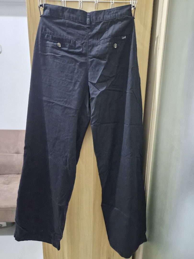Levi's Black Casual Pants Trousers (Category: Jeans) located in Mandaluyong City. Submitted by joyce1593 (Listing ID 1469255585, Image 3). Description: - Brand: Levi's - Colors available: Dark navy or black - Closure: Button closure with zip fly - Design: Front pleats with a clean, classic straight fit - Pockets: Back welt pockets with button closures and iconic small Levi's brand tag - Condition: Clean fabric throughout.