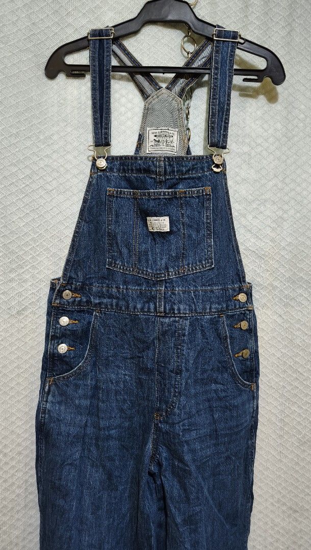 Levi's Denim Overalls Dark Wash (Category: Jumpsuits) located in La Paz. Submitted by carou89146 (Listing ID 1469180606, Image 2). Description: - Brand: Levi Strauss & Co. - Style: Dark wash denim overalls with classic bib design - Material: 100% cotton, durable and machine washable - Details: Adjustable shoulder straps, metal side buttons, front chest pocket with woven logo patch - Back: Signature back pockets with iconic red tab needs washing e