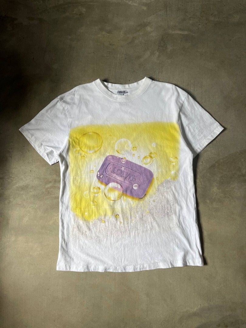 LOEWE soap print t-shirt (Category: Tshirts & Polo Shirts ) located in Polangui. Submitted by jamessaintlaurent (Listing ID 1469193426, Image 1). Description: This is a Loewe Soap-Print T-Shirt in white, featuring a purple-and-yellow graphic of a bar of soap surrounded by bubbles and a spray background..